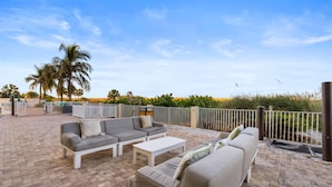 Een terras met buitenmeubilair, inclusief een zithoek, salontafel en een balustrade.