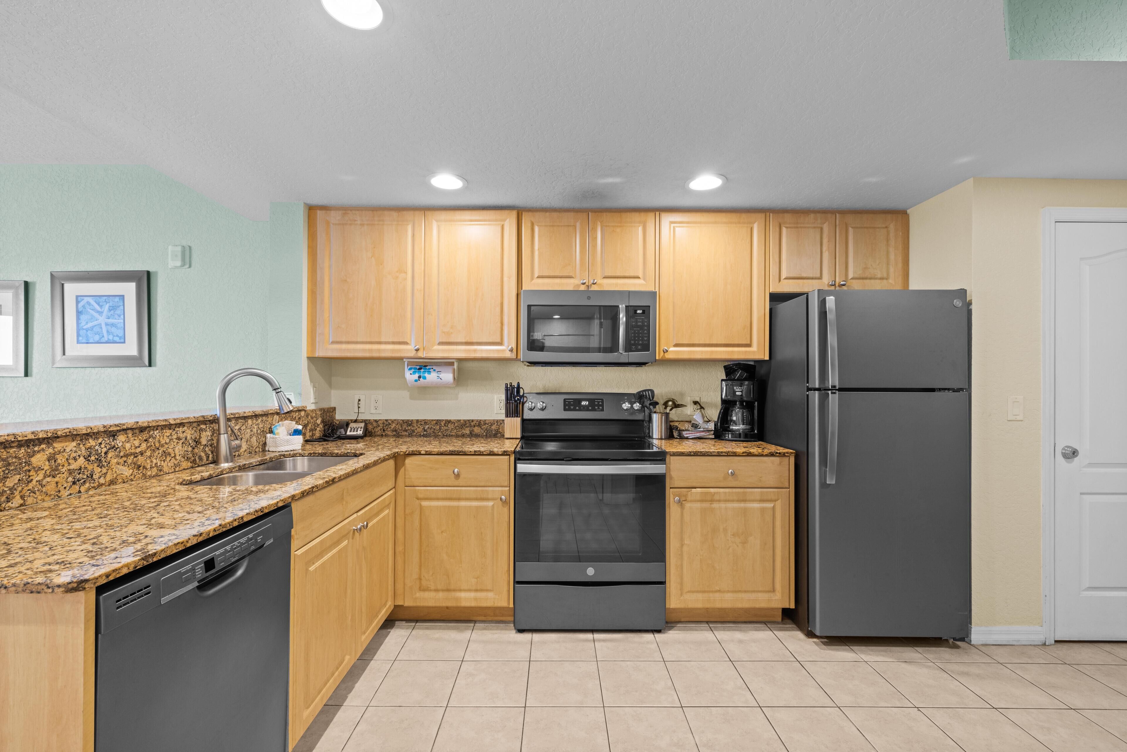 A kitchen with wooden cabinets, a stainless steel refrigerator, a microwave, an oven, and a dishwasher.