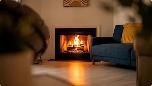 A living room with a fireplace, a blue sofa, and a yellow throw pillow.