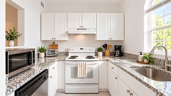 A modern kitchen with white cabinets, a stainless steel stove, a microwave, and a granite countertop. - Suite Life Wilmington-Spacious, Pet-Friendly 1BR, Pool, Balcony, Prime Location (Wilmington)