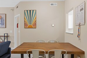 Una sala de conferencias con una mesa de madera, sillas blancas, un cuadro abstracto grande y un extintor.