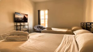 A hotel room with two beds, a TV on the wall, and a window.