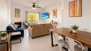 A modern living room with a fireplace, a sofa, a dining table, and a TV. - Suite Life Wilmington-Spacious, Pet-Friendly 1BR, Pool, Balcony, Prime Location (Wilmington)