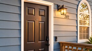 A house with a dark brown front door, a mailbox, and a lit wall-mounted lantern. - Suite Life Wilmington-Spacious, Pet-Friendly 1BR, Pool, Balcony, Prime Location (Wilmington)