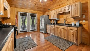 A wooden cabin kitchen with a refrigerator, stove, and wooden cabinets. - Serene Retreat, Private Setting, Near Muir Valley Climbing & Redpoint BBQ (Rogers)