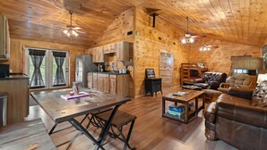 A wooden cabin interior with a dining table, kitchen area, and seating area. - Serene Retreat, Private Setting, Near Muir Valley Climbing & Redpoint BBQ (Rogers)