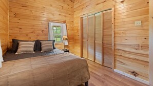 A wooden-paneled bedroom with a bed, pillows, a nightstand, a lamp, and a window. - Serene Retreat, Private Setting, Near Muir Valley Climbing & Redpoint BBQ (Rogers)