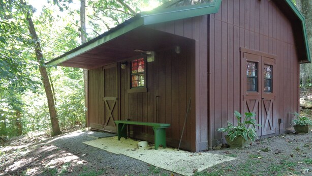 A rustic wooden cabin with a covered porch, a bench, and potted plants. - The Cottage in the Woods, near Deersville and Tappan and Clendening Lakes (Deersville)