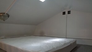 A small, unadorned room with a single bed, a slanted ceiling, and a visible vent. - The Cottage in the Woods, near Deersville and Tappan and Clendening Lakes (Deersville)