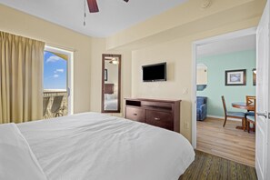 A hotel room with a large bed, a TV, a dresser, a desk, and a chair.