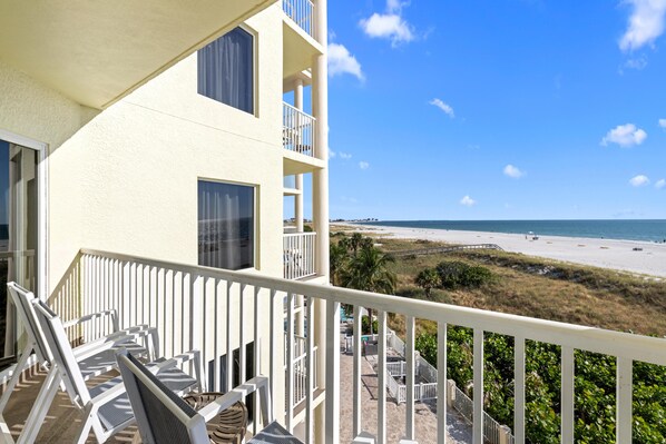 A balcony with white railings overlooking a beach.