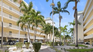 A multi-story hotel with balconies, palm trees, and a parking area.