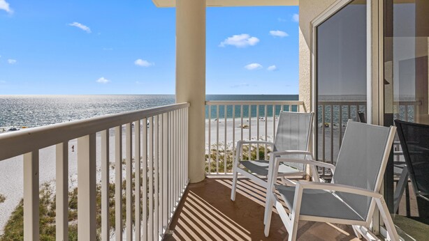 A balcony with a view of the ocean, white chairs, and a glass door. - 3/3 Penthouse Condo with Epic Beach Views (Treasure Island)