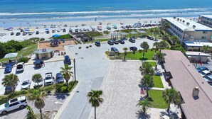 Ein Parkplatz am Strand mit Blick auf das Meer, ein Spielplatz und ein Gebäude mit rotem Dach.