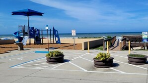 Ein Parkplatz mit Behindertenparkplätzen, einem Spielplatz und Blick auf den Strand.