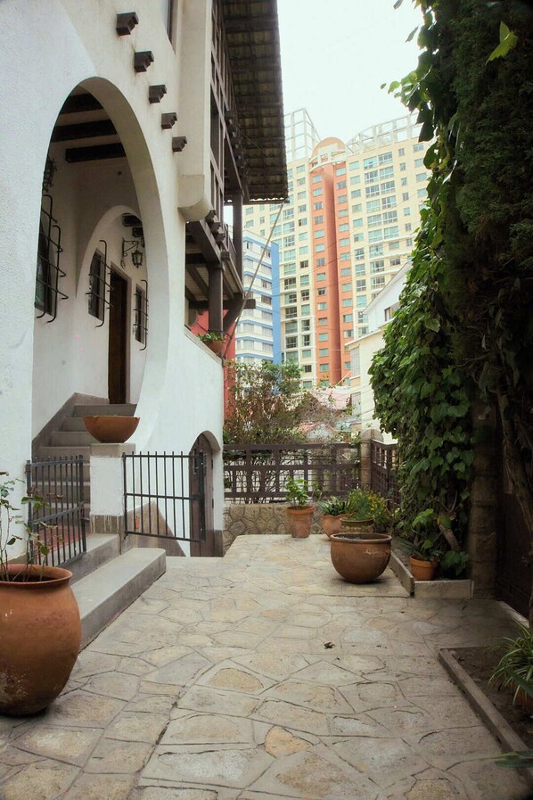 A courtyard with stone flooring, potted plants, and a staircase leading to an upper level.