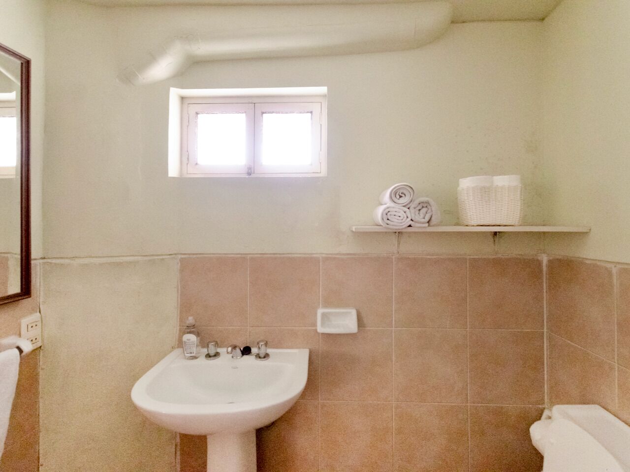 Ein Badezimmer mit Waschbecken, Fenster und Ablagefläche mit Handtüchern.