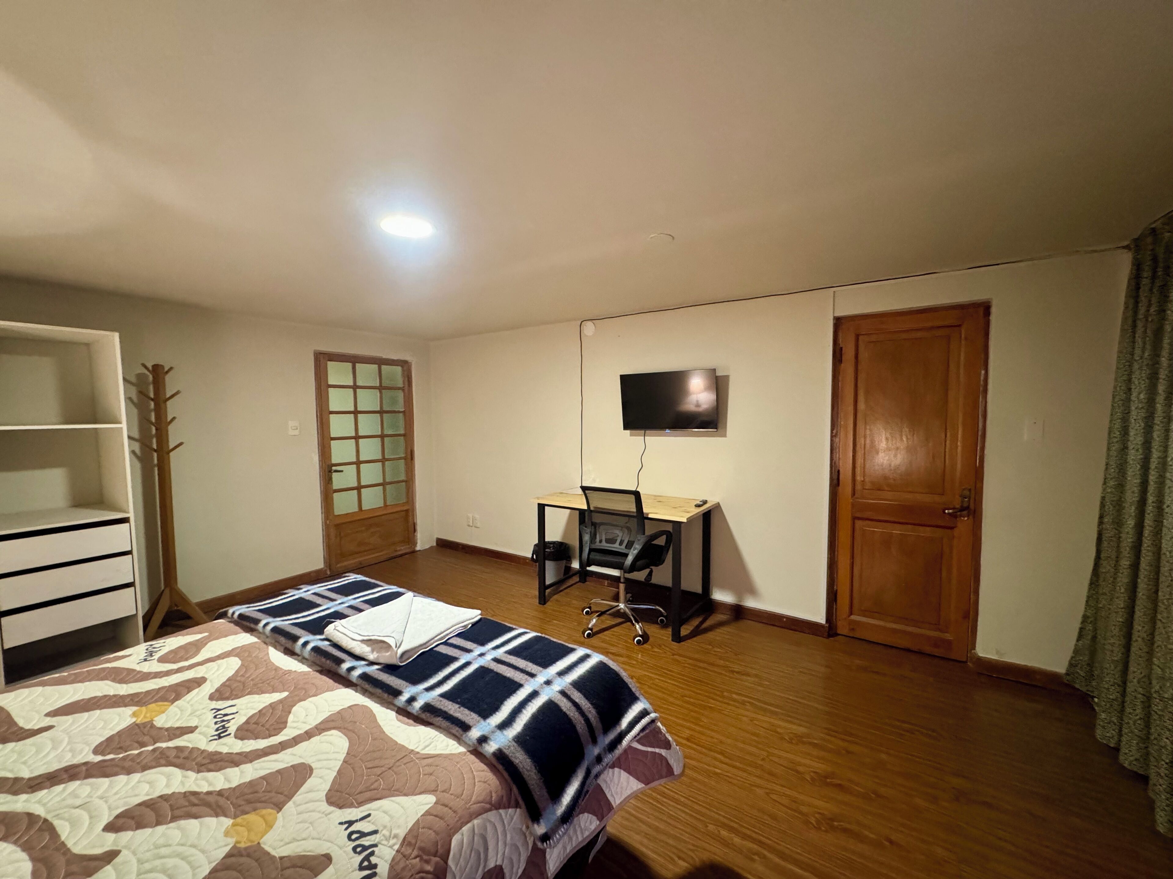 Une chambre à coucher comprenant un lit, un bureau, une télévision et une armoire.