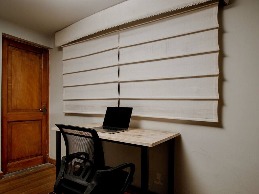 A small office space with a wooden desk, a laptop, and a chair.