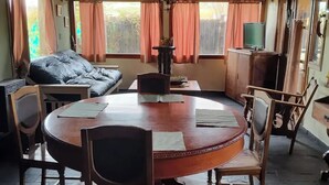 Une pi èce chaleureuse avec une table à manger en bois entourée de chaises, d’un canapé et d’un téléviseur.