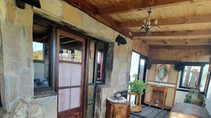 Un intérieur rustique avec des murs en pierre, des poutres en bois, une table en bois et un banc.