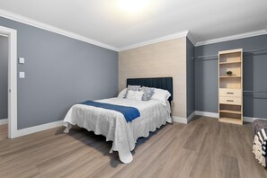 Een slaapkamer met een bed, een houten garderobe en een lichtgekleurde vloer.