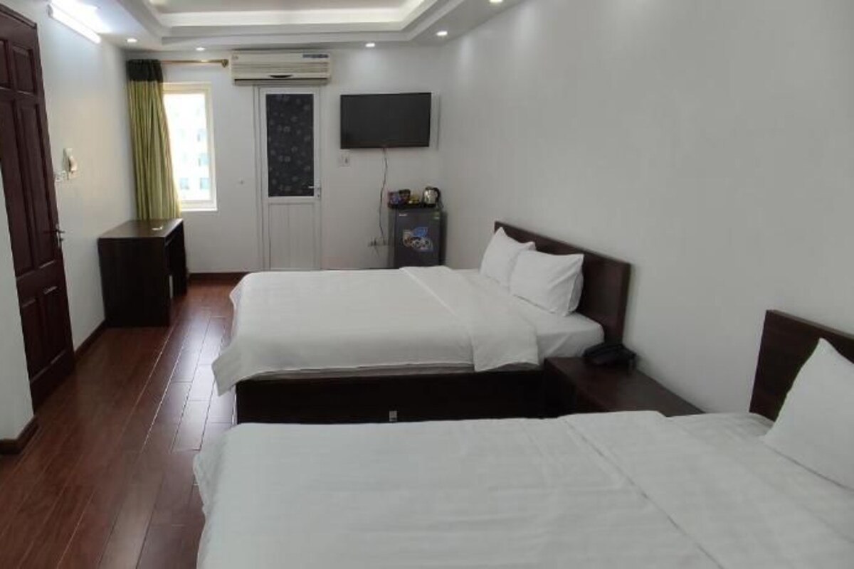 Habitación de hotel con dos camas, televisor, escritorio y armario.