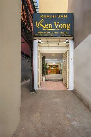 L’entrée d’un hôtel, avec un panneau indicateur, un comptoir d’accueil et une plante en pot.