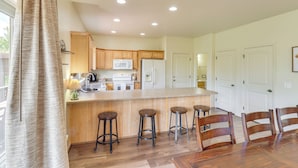 Una cocina moderna con armarios de madera, una isla central con taburetes y un comedor con sillas de madera.