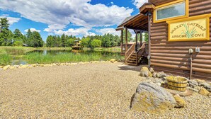 Una cabaña rústica con camino de grava, una terraza de madera y un letrero que dice "Snazzy Cattails Apache Cove."