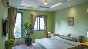 A bedroom with a bed, a potted plant, a desk, and a window with curtains. - Ben Thanh Homestay And Apartment (Ho Chi Minh Municipality)