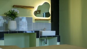 A modern bathroom with a white sink, a mirror, and a potted plant. - Ben Thanh Homestay And Apartment (Ho Chi Minh Municipality)