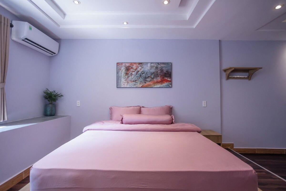 Un dormitorio con cama, luz de techo, equipo de aire acondicionado, estante en la pared y ventana con cortinas.