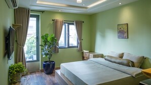 A bedroom with a bed, a potted plant, a desk, and a window with curtains. - Ben Thanh Homestay And Apartment (Ho Chi Minh Municipality)