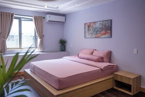 Un dormitorio moderno con cama, una mesita de noche pequeña, una planta en maceta y una ventana con cortinas.