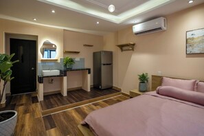 Un dormitorio moderno con una cama grande, una mesita de noche, un armario empotrado y un pequeño rincón de descanso con una silla y una mesa.