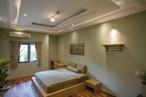 Un dormitorio con cama, mesitas de noche, un armario, un equipo de aire acondicionado, una ventana con cortinas y un estante en la pared.