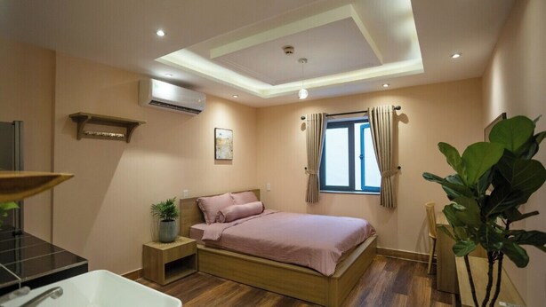 A bedroom with a bed, bedside table, and a large window with curtains. - Ben Thanh Homestay And Apartment (Ho Chi Minh Municipality)
