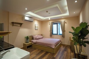 Une chambre à coucher avec un lit, une table de chevet et une grande fenêtre avec des rideaux.