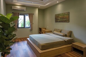 Ein Schlafzimmer mit einem großen Bett, einem Holz-Kopfende, einem Nachttisch, einem Fenster mit Vorhängen und einer Topfpflanze.