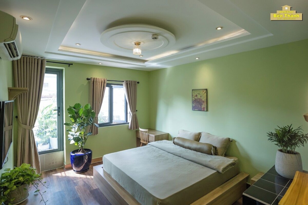 Un dormitorio con cama, escritorio, silla y planta en maceta.