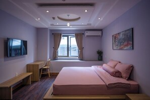 Une chambre à coucher avec un lit, un bureau, une chaise, un téléviseur et une fenêtre avec des rideaux.