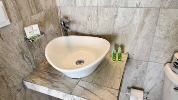 A bathroom with a white sink, a mirror, a towel dispenser, and a toilet.