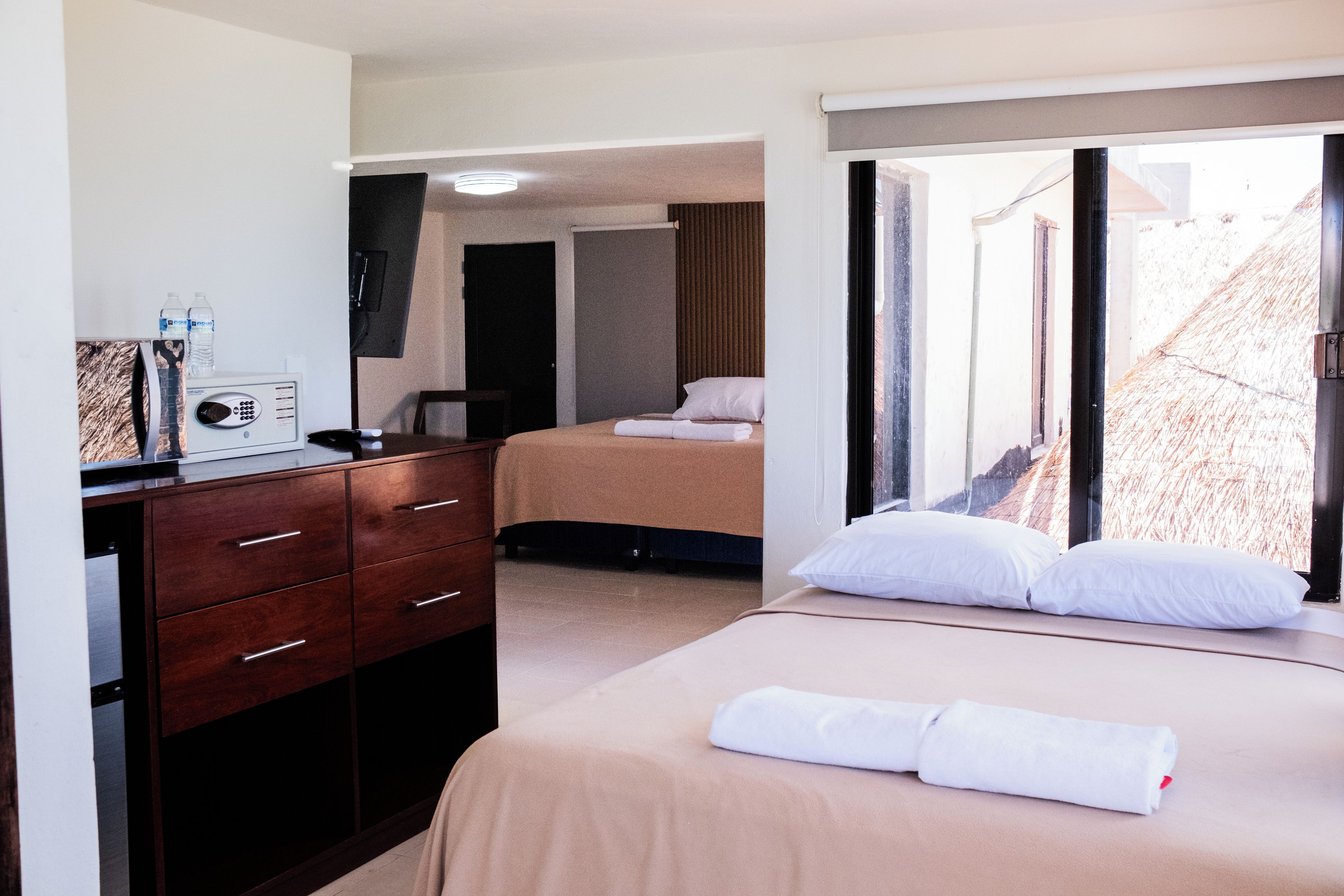 A hotel room with a bed, a desk, a chair, a TV, and a window with a view of the outside.
