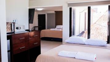 A hotel room with a bed, a desk, a chair, a TV, and a window with a view of the outside.