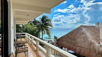 A balcony with wooden chairs and a thatched-roof structure.