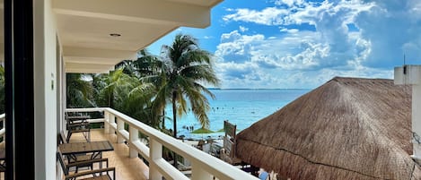 A balcony with wooden chairs and a thatched-roof structure.