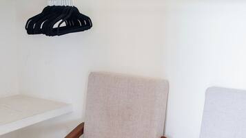Two wooden chairs with fabric seats, a white shelf, and a window with a view.