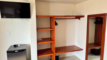 A room with a built-in wooden shelving unit, a television mounted on the wall, and a small table with a power outlet.