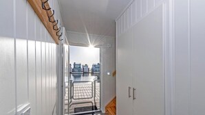 A corridor with a wooden wall and metal hooks, leading to a view of a dock and water. - Awesome ship in Olpenitz with sauna (Olpenitz)